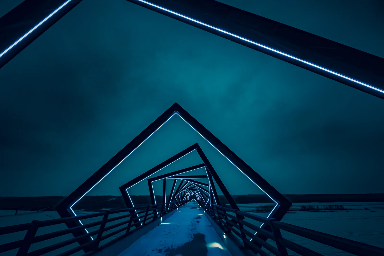 Steel bridge frames recede in sequence under a deep blue evening sky.