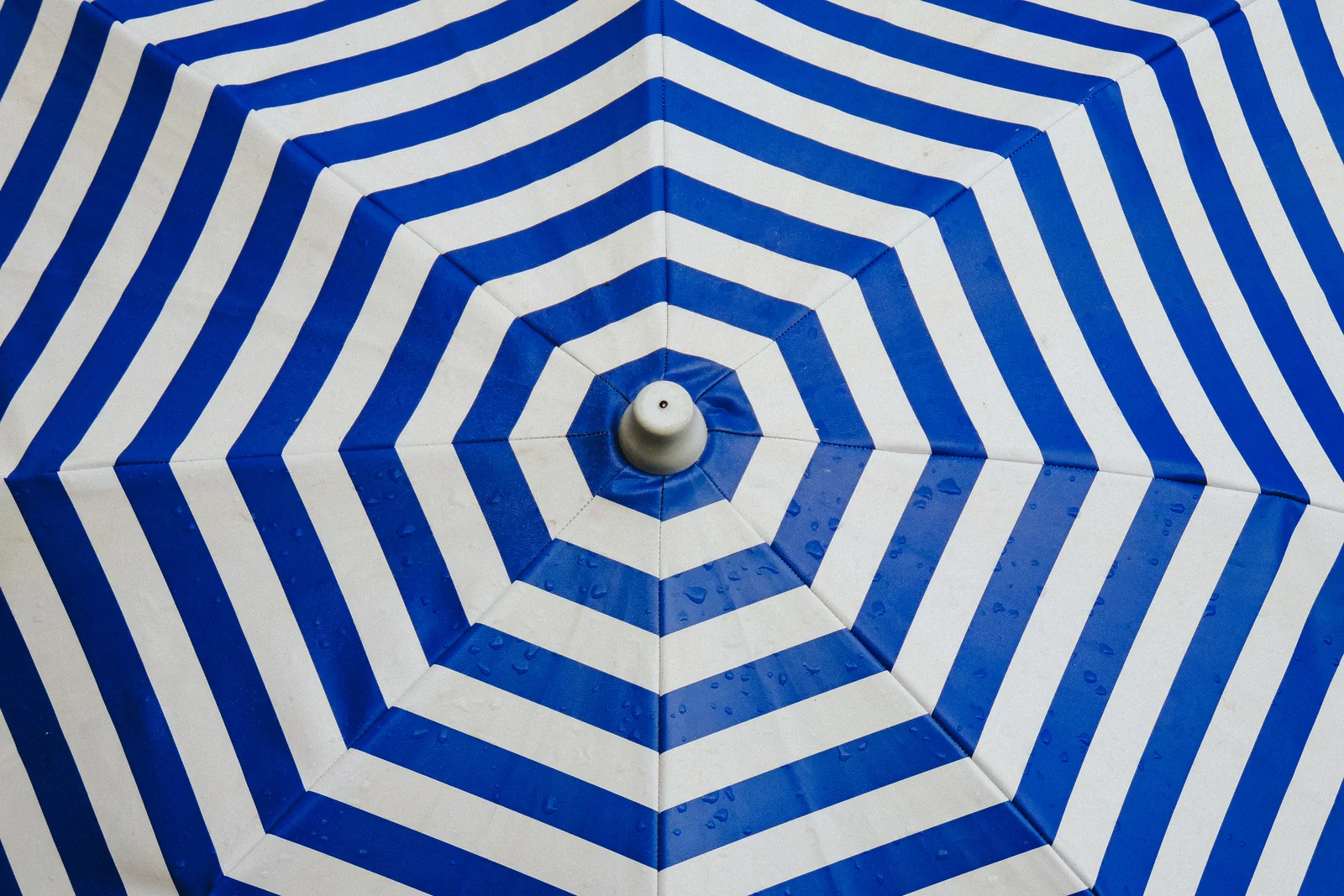 A blue and white striped umbrella seen from above, close up.